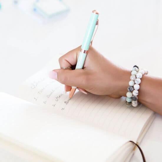 hand holding a pen writing to do list - self care ideas for moms