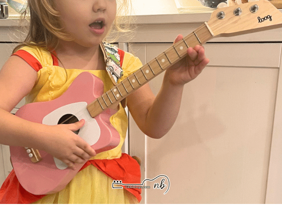 girl playing loog mini acoustic guitar