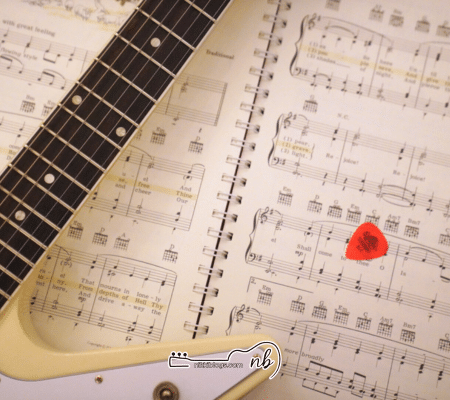 christmas worship songs book open with guitar and pick on top